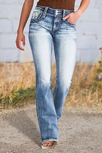 Gros plan sur un jean brodé pour femme avec délavage et taille à double boutonnage