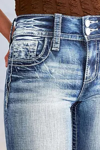 Gros plan sur un jean en denim avec coutures blanches et double boutonnage taille