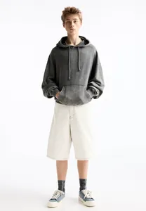 Men's casual white denim shorts styled with a grey washed hoodie and sneakers.