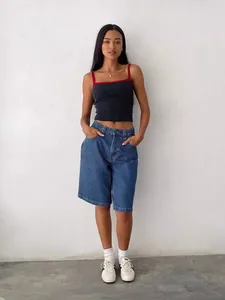 Full body shot of a model wearing high-waisted denim shorts in a minimalist setting