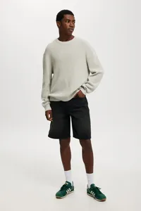 Men's casual black denim shorts styled with light grey knit sweater for a modern look