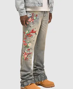 Close-up detail of floral and crane embroidery on men's vintage wash denim straight jeans