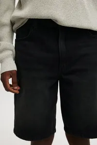 Close-up detail of black denim shorts showing fabric texture and pocket design