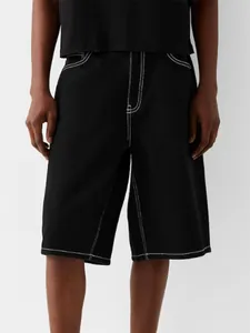 Detail shot of men's black denim shorts featuring striking white contrast stitching.