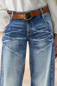 Detail of women's straight-leg denim jeans with a brown belt and faded wash effect.