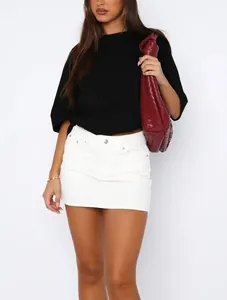 Model wearing a slim-fit white denim mini skirt with a black t-shirt and red bag.