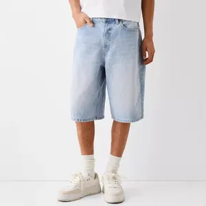 Men's loose fit light blue wash denim shorts in minimalist studio setting