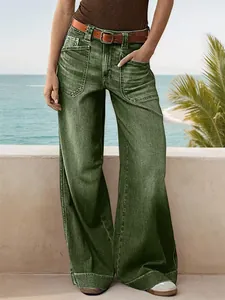 Close-up detail of vintage green wide-leg denim jeans for women in a seaside setting