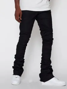 Detailed view of men's black stacked denim pants featuring stacked ruffles and raw hem