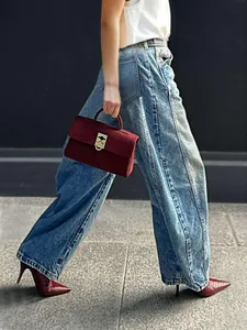 Side view of model wearing vintage washed wide-leg denim jeans on a city sidewalk