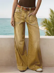 Macro detail view of women's vintage yellow wide-leg straight denim jeans on a model.