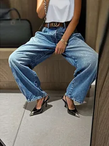 Detail view of stylish retro washed wide-leg blue jeans paired with black pointed heels