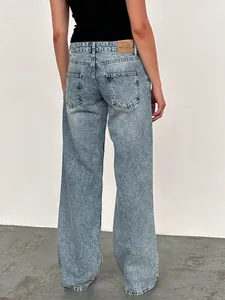 Vue détaillée du jean droit délavé à l'acide avec poches arrière et patch logo noir.