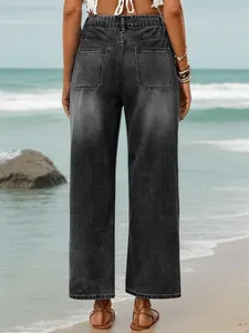 Detailed back view of relaxed fit grey denim cropped jeans for women on a sunny beach.