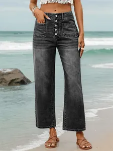 Detail of high-waisted washed black denim jeans with five-button fly and patch pockets.