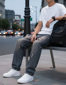 Detailed view of men's distressed straight-leg denim jeans in a lifestyle street setting