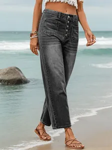 Close-up of women's washed black button-fly denim pants on a beach setting