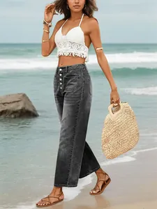 Women's high-waisted button-fly wide-leg jeans in washed black on a beach setting.