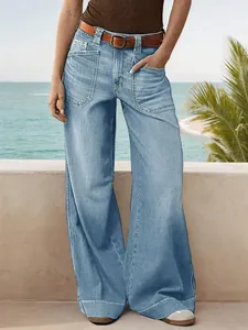 Detailed view of loose wide-leg denim jeans with large front pockets on a model outdoors