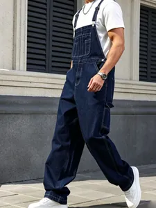 Detail view of men's vintage dark blue loose straight-leg denim overalls on model.