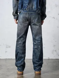 Back view of men's vintage distressed wide leg straight denim jeans in industrial setting
