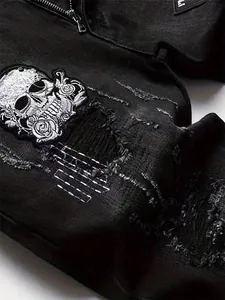 Macro detail of intricate skull and rose embroidery on black ripped high-street denim pants