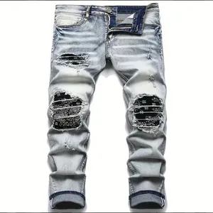 Close-up of light blue distressed jeans with black paisley patches inside rips