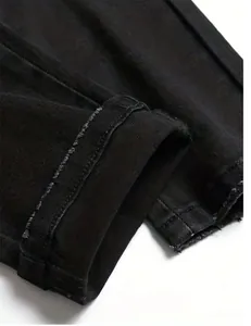Detailed close-up of high-quality stitching on black denim jeans leg opening