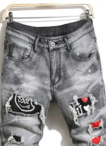 Gros plan d'un jean gris déchiré avec écussons COOL et cœur, effet graffiti