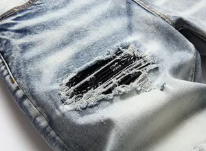 Close-up of ripped denim details with black paisley patch lining.