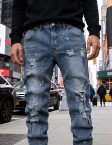 Men's distressed slim-fit ripped jeans with paint splatter detail in city street setting