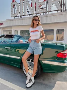 Model posing in casual high-waisted light blue denim shorts with frayed hem design