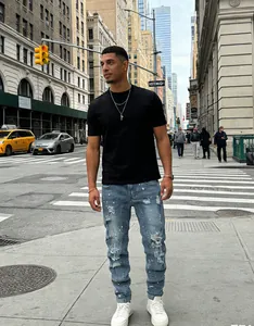 Male model wearing blue distressed slim fit jeans with paint splatter detail on street