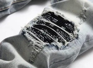 Close-up of distressed denim jeans featuring ripped detail with black bandana patch