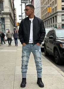 Male model wearing slim fit distressed jeans with paint splatter in urban street setting