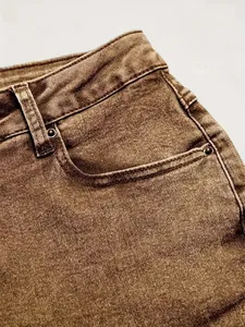 Close-up view of pocket and texture detail on brown vintage washed denim jeans