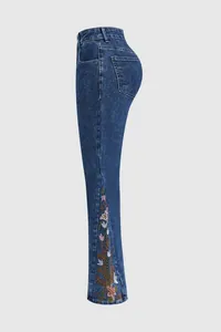 Detailed view of floral embroidery on the side panel of flared blue denim jeans.