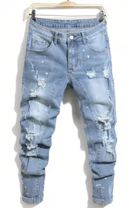 Macro view of light wash slim denim jeans showing distressed ripped details and paint splashes