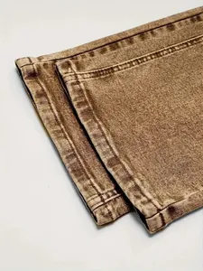 Detailed macro view of retro brown washed denim jeans hem with neat double-row stitching.
