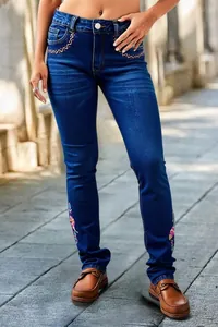Detailed view of women's slim-fit blue jeans with colorful bohemian embroidery details