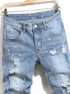 Λεπτομέρεια από μπλε skinny τζιν με σκισίματα και λευκές πιτσιλιές μπογιάς