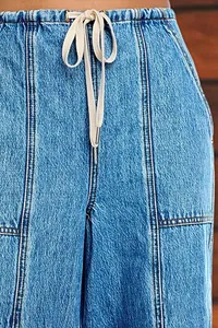 Détail d'un jean avec taille élastique à cordon et surpiqûres verticales décoratives