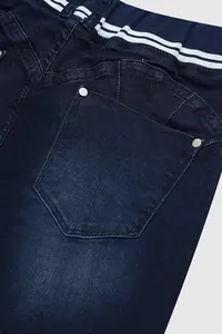 Gros plan détaillé de la poche arrière et des rivets d'un jean en denim bleu foncé ajusté
