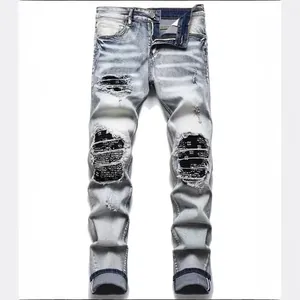 Light blue distressed slim fit jeans with black knee patches and ripped details.
