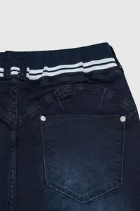 Gros plan sur la taille élastique rayée et la poche arrière d'un jean bleu foncé