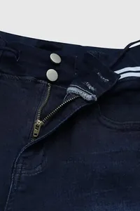 Détail en gros plan de la fermeture à glissière et des deux boutons sur un jean bleu marine.