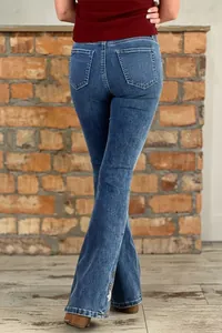 Detailed back view of stylish ladies' flare jeans with delicate flower embroidery on the hem.