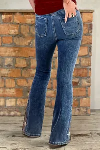 Back view of women's embroidered flare jeans with floral patterns on a brick background