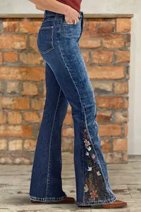 Detail of women's flare jeans with intricate floral embroidery on the side of the leg.