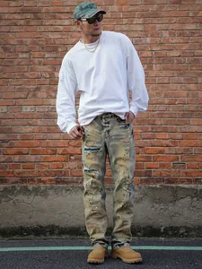 Detailed view of men's vintage distressed jeans with paint splatters and ripped knee detail.